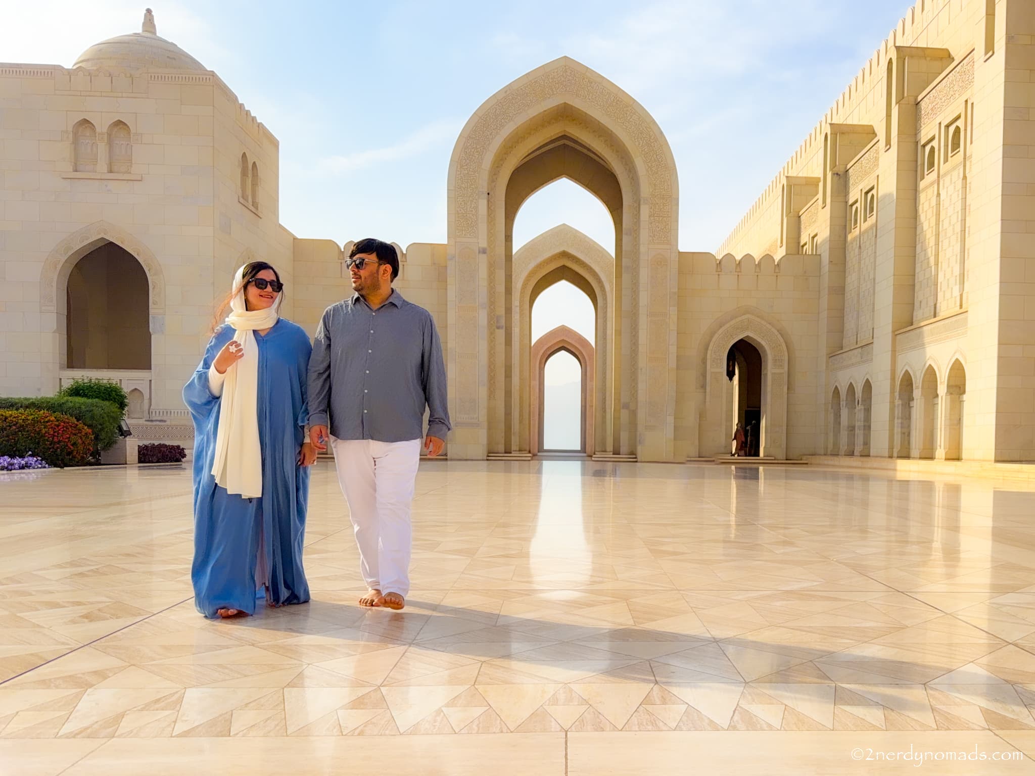Urvi and Animesh standing in front of Sultan Qaboos Grand Mosque in Muscat, Oman.