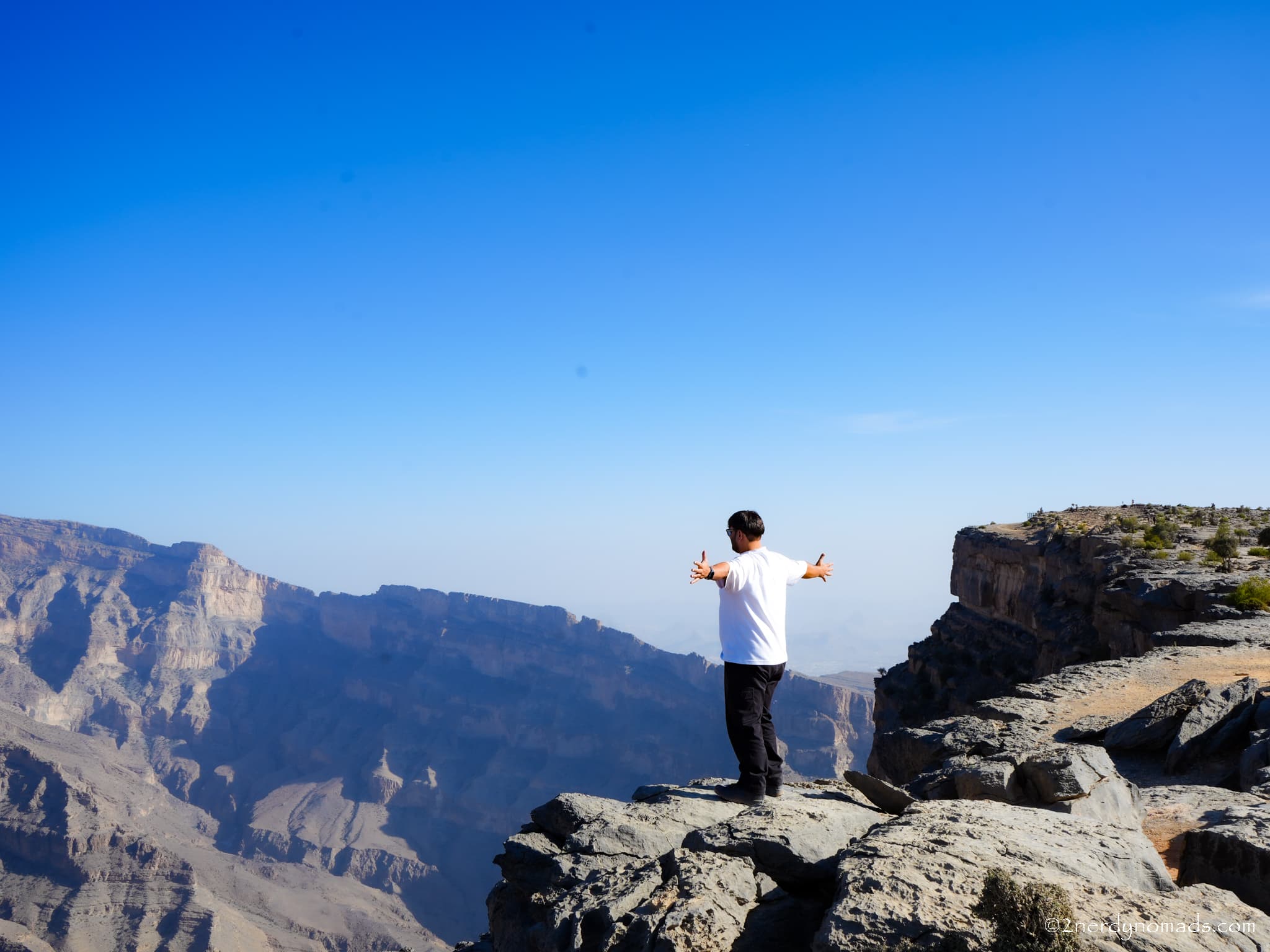 Animesh standing on a mountain peak in Oman, enjoying the rugged mountain landscape.