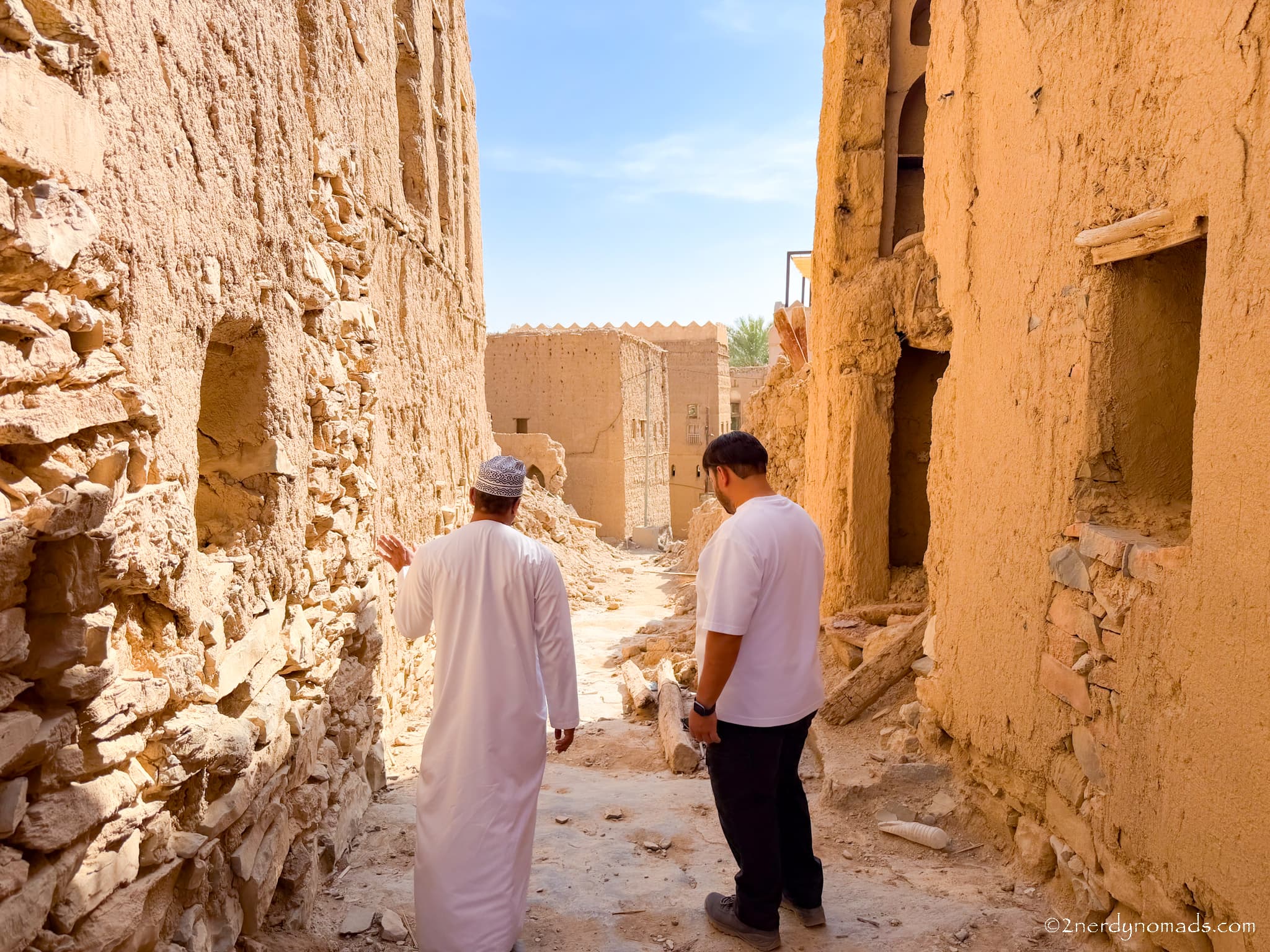 Animesh walking through a traditional old village in Oman with a local resident, learning about the village's history and heritage.